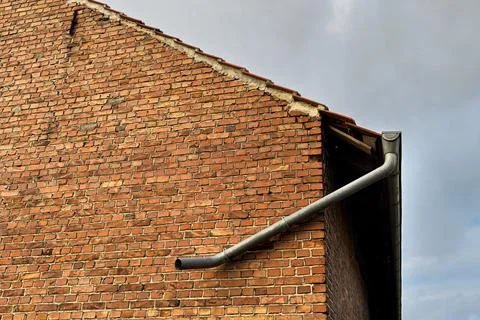 Unique brick wall with an interesting gutter on a cloudy day Stock Photos