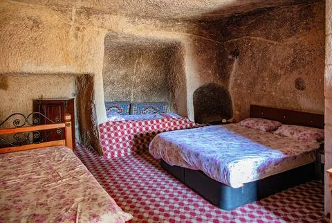 Unique cave accommodation showcasing rustic charm and comfortable beds in a.. Stock Photos