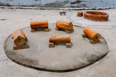 Unique Circular Arrangement of Log Stools and Brick Well near the Coastline Stock Photos
