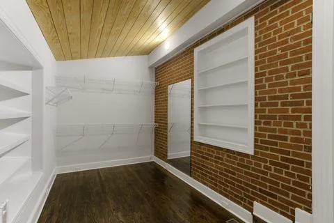 Unique Closet Space With Brick Wall, Wooden Ceiling, And Mounted Shelves. Stock Photos