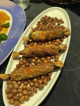 Unique dish of stuffed vegetable rolls served on a plate with roasted nuts .. Stock Photos