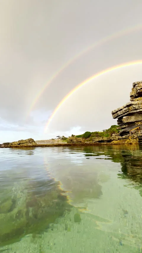 Unique double rainbow viewed from marine tide pool on coastline Stock Footage 340135114