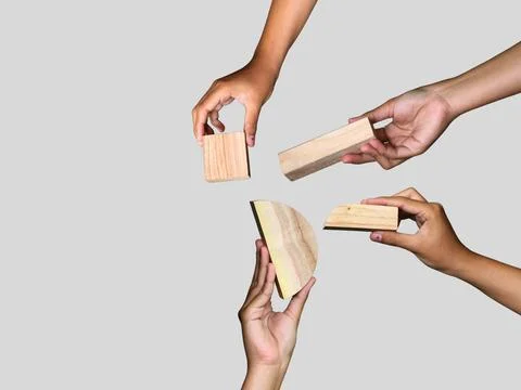 Unique hands holding a different piece of the wooden puzzle, teamwork Stock Photos