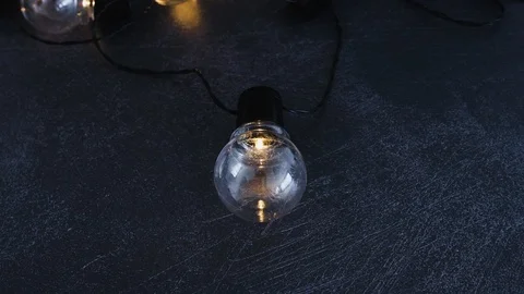 Unique lightbulb isolated in front of group of others shining on dark desk me Stock Footage 116646064