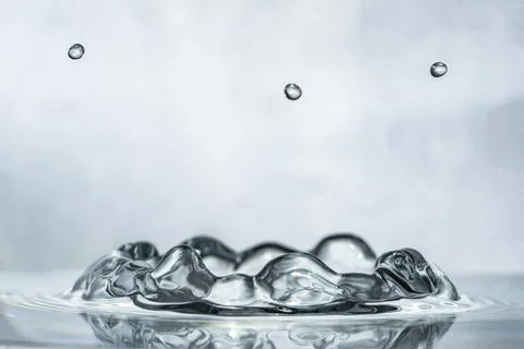 Unique liquid ripple effect after water drop falls in water, bright background Stock Photos