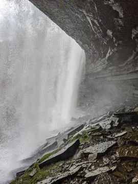 A unique perspective behind a waterfall and underneath a overhang Stock-Fotos