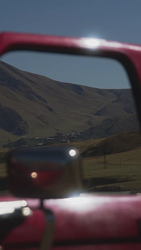 Unique Perspective of a Mountain Village through the Rearview Mirror of a Red Stock Footage 273794476
