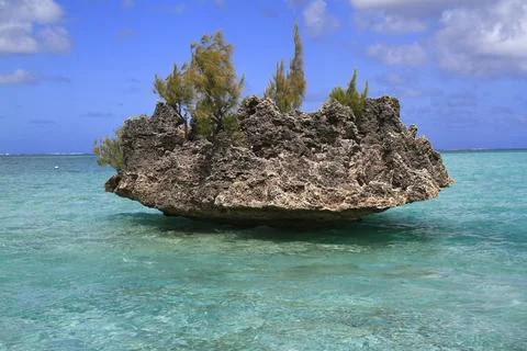A unique rock formation with sparse trees rising from the stunning turquois.. Stock Photos