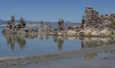 Unique rock formations reflected in calm water under a clear blue sky at Mo.. Stock Photos