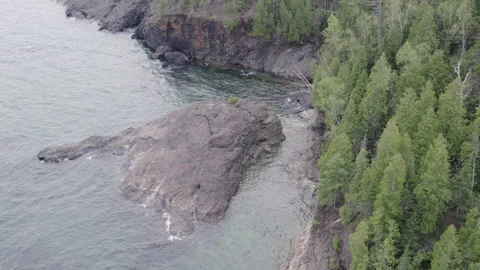 Unique rock island surrounded by cliffs and pines, 4k, slow-mo drone shot Stock Footage 243534265