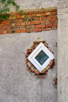 Unique round window framed by exposed bricks on a weathered wall outdoors Stock Photos