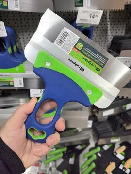 Unique scraper tool held by a hand inside a hardware store aisle Stockfoto's