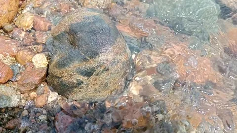 Unique small rocks on the edge of the beach that are hit by small waves Stock Footage 277017131