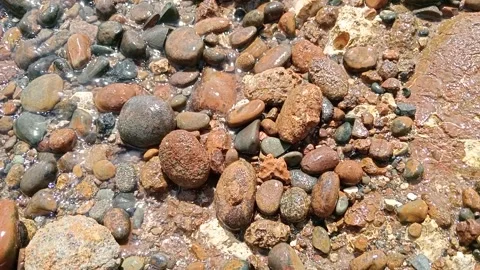 Unique small rocks on the edge of the beach that are hit by small waves Stock Footage 277017511