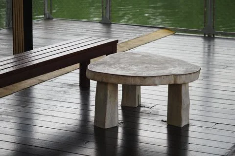 Unique table and bench beside water on a wooden deck 스톡 사진
