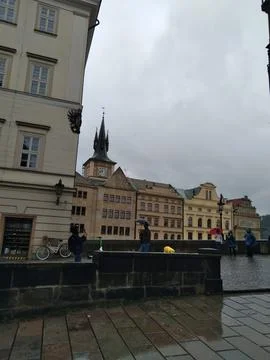 A unique tower with a clock surrounded by buildings Stock Photos