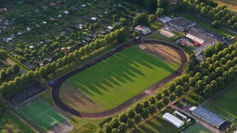 Unique tripod elevated perspective of green football field and running track dur Stock Footage 337408682