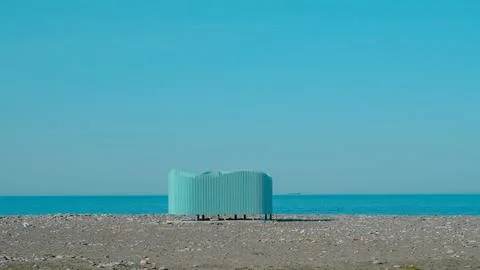 Unique turquoise structure on rocky beach with clear blue sky and ocean Stock Photos