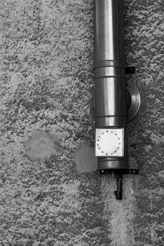 Unique wall-mounted clock design above textured gray surface in urban setting Fotos Stock