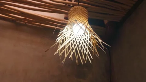 Unique woven bamboo ceiling lamp hanging from a rustic wooden ceiling. Video stock 343407306