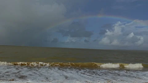 UniqueBright rainbow arcs over a stormy green sea under heavy clouds on the Stock Footage 324806499