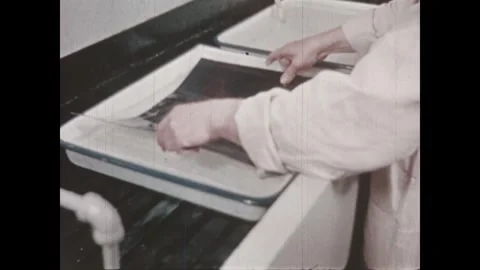 United States 1940s: Man dips a blue paper into a hot water bath. He turn the Stock Footage 346423285