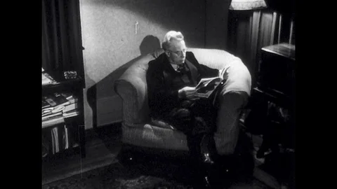 UNITED STATES: 1940s: Man sits in chair reading newspaper. Girl takes off apron. Stock Footage