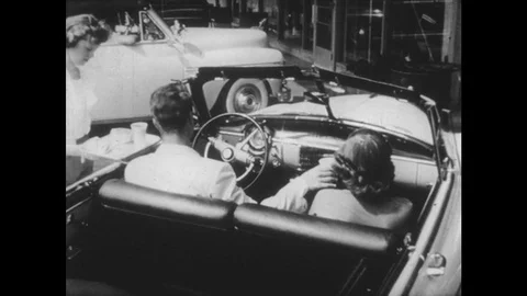 UNITED STATES: 1950s: man and lady in car. Drive thru theatre production. Stock Footage