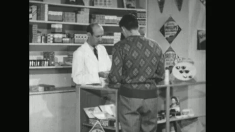 UNITED STATES 1950s: A man in a patterned shirt stands at an electronics Stock Footage 337061082