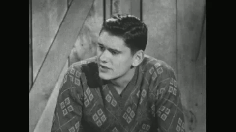 UNITED STATES 1950s: A man in a patterned kimono stands and speaks with another Stock Footage 337061171