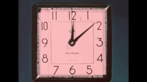 UNITED STATES 1950s: A square wall clock with a white face and black numerals is Stock Footage 336139906