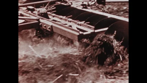 UNITED STATES 1950s: Tractor pulls a disc harrow through a dry field. Curved Stock Footage 312528597