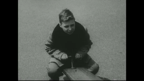 UNITED STATES 1950s: Two Boys Play on See Saw as Heavier Boy Lifts Lighter Boy Stock Footage