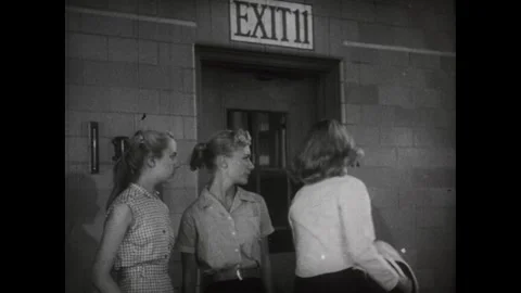United States 1950s: Two young women stand near a doorway marked "EXIT" with Stock Footage 344814347