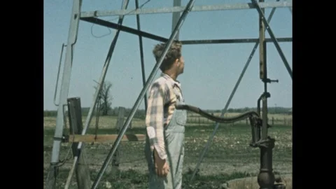 United States 1950s: Windmill with boy at base pumping water. Stock Footage 304285437