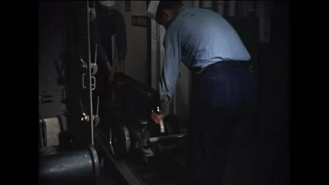 UNITED STATES - 1955 - Two men push a cart down the track. Another man loads a Stock Footage 322762878