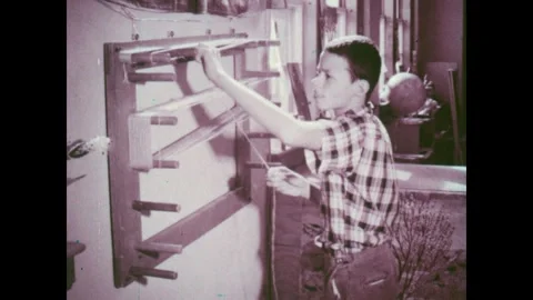 UNITED STATES 1960s: Boy threading yarn onto frame. Hands pulling yarn strands Stock Footage 318912704