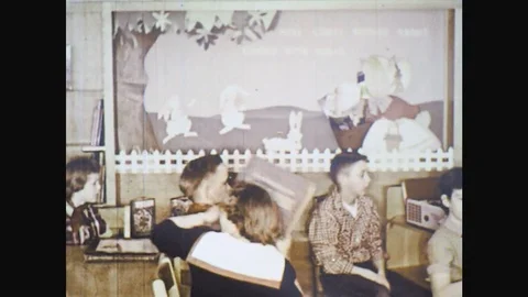 UNITED STATES: 1960s: students pass around book. Girl opens book. Child asks Stock Footage
