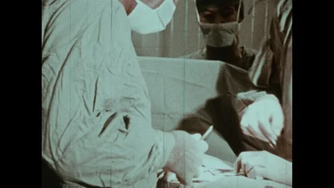 United States 1970s: Doctors operating on patient, tilt down. Nurse handing Video stock 322176239