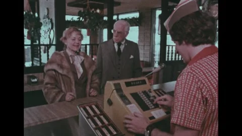 United States 1970s: An elderly couple stands at a fast-food counter served by a Vídeo Stock 343397953