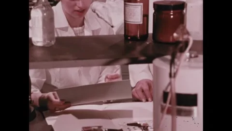 UNITED STATES - 1972 - Scientists write data on clipboards and pour chemicals as Stock Footage 341971137