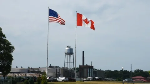 The United States of America (USA) and Canada flags fly at the border Stock Footage