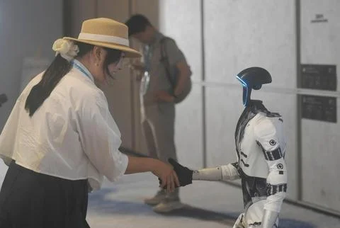 Unitree Robotics' G1 humanoid robot shakes hands with a guest at an AI indust Foto stock