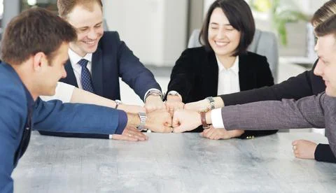 Unity and teamwork concept of young business people folding their hands toget Stock Photos