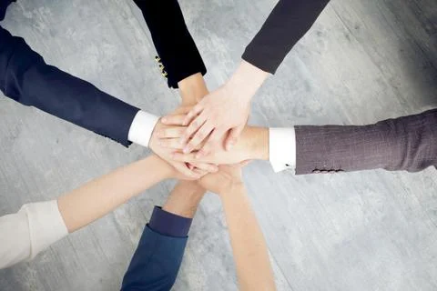 Unity and teamwork concept of young business people folding their hands together Stock Photos