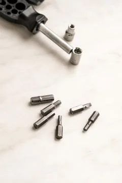 Universal engineer hand tool screwdriver and scattering bits on wooden backgr Stock Photos