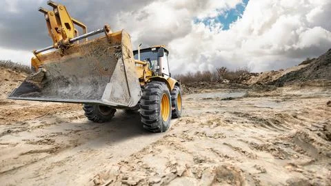 A universal excavator loader is actively engaged in moving dirt on a constr.. Stock Photos