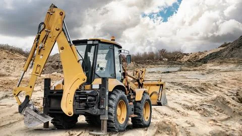 A universal excavator loader is on a construction site digging and moving e.. Stock Photos