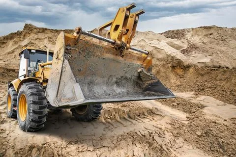 A universal excavator loader lifts a large load of dirt at a construction s.. Stock Photos