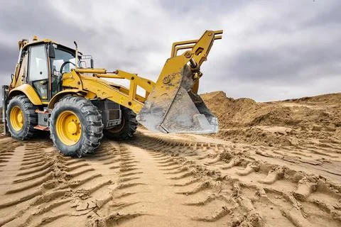 A universal excavator loader is moving dirt on a construction site. The mac.. Stock Photos